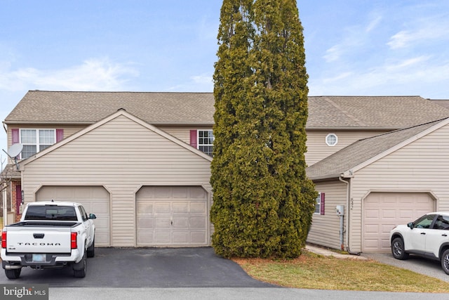 view of front of home featuring a garage, driveway, and roof with shingles