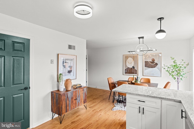 dining space featuring light wood-style floors, baseboards, and visible vents