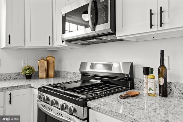 kitchen featuring appliances with stainless steel finishes, white cabinetry, and light stone countertops