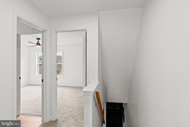 hallway with carpet floors, an upstairs landing, and baseboards