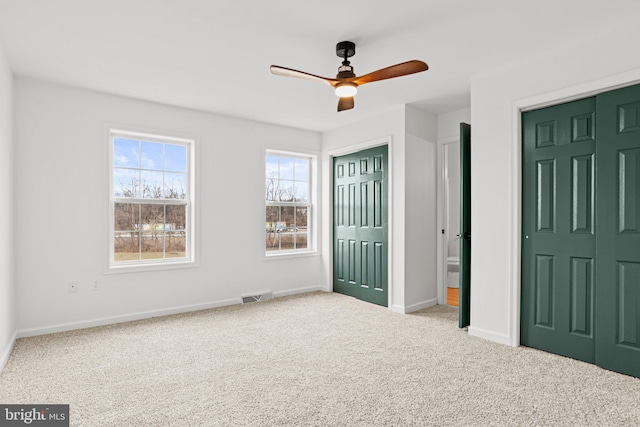 unfurnished bedroom with carpet floors, visible vents, ceiling fan, and baseboards