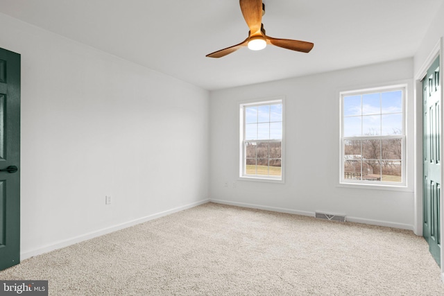 spare room featuring baseboards, carpet flooring, visible vents, and a ceiling fan