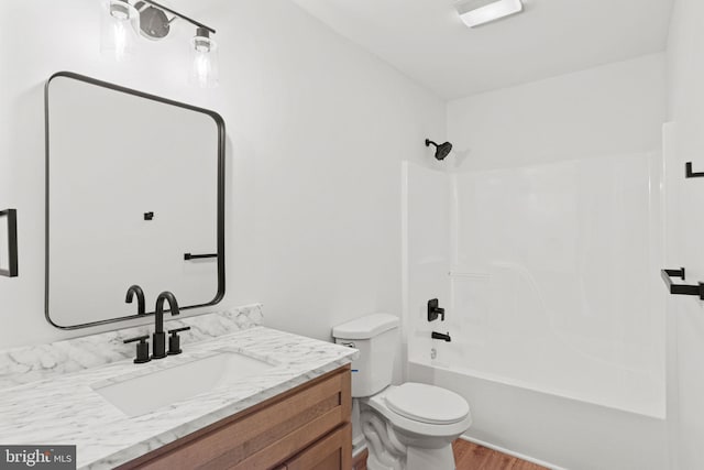 bathroom featuring toilet, tub / shower combination, wood finished floors, and vanity