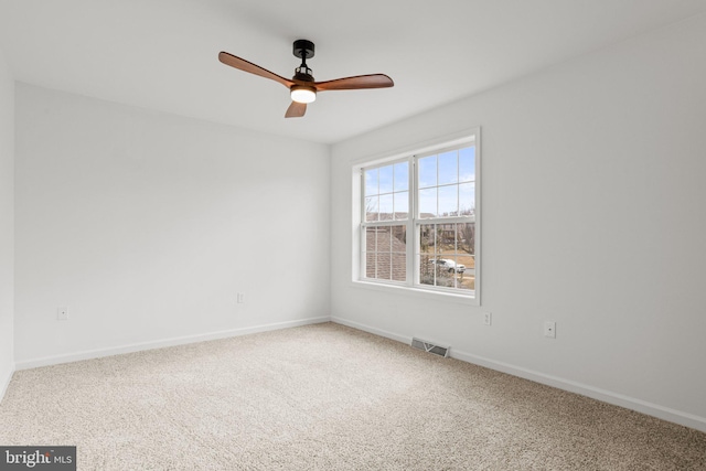 carpeted empty room with ceiling fan, visible vents, and baseboards