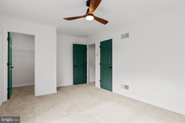 unfurnished bedroom with a closet, carpet flooring, visible vents, and a walk in closet