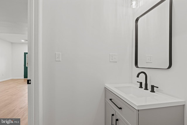 bathroom with wood finished floors, vanity, and baseboards