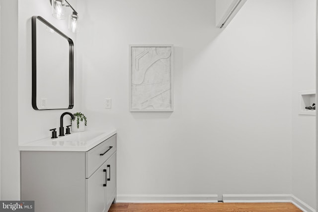 bathroom featuring baseboards, wood finished floors, and vanity