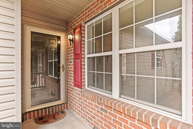 entrance to property with covered porch and brick siding