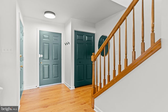 foyer with stairway, baseboards, and wood finished floors