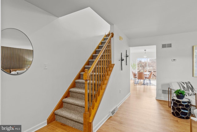 staircase with wood finished floors, visible vents, and baseboards