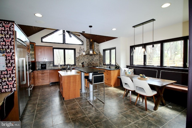 kitchen featuring decorative backsplash, a center island with sink, a kitchen bar, recessed lighting, and a warming drawer