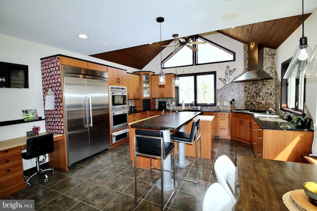 kitchen featuring lofted ceiling, dark countertops, wall chimney exhaust hood, wooden ceiling, and appliances with stainless steel finishes