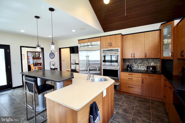 kitchen with a sink, stainless steel appliances, tasteful backsplash, vaulted ceiling, and glass insert cabinets