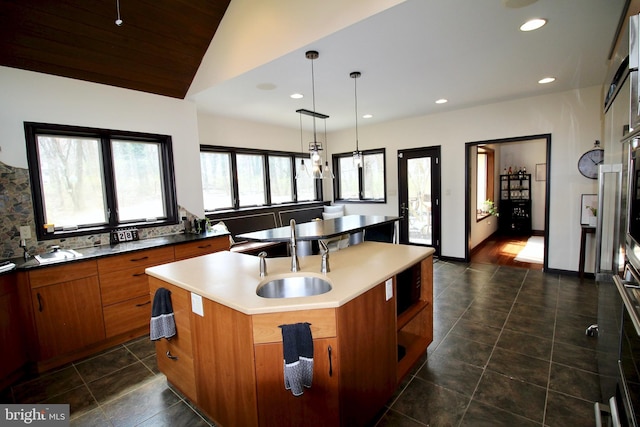 kitchen with brown cabinets, recessed lighting, a sink, and a kitchen island with sink