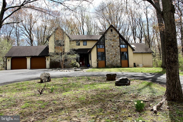 view of front facade featuring a garage, a front lawn, aphalt driveway, stone siding, and stucco siding