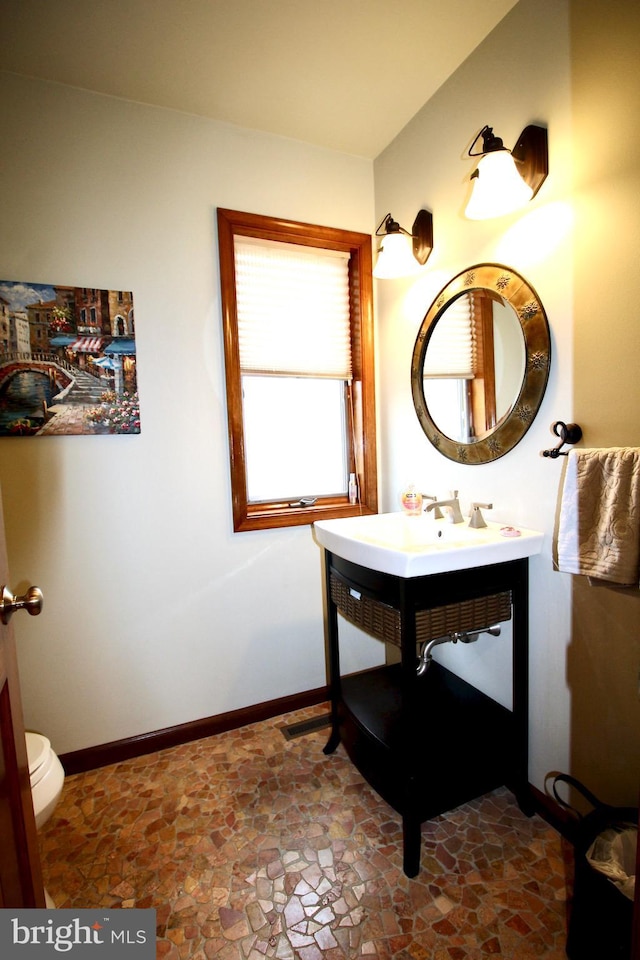 bathroom featuring vanity, baseboards, and stone finish flooring