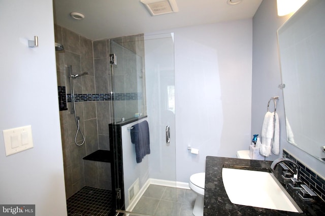 bathroom with vanity, toilet, tile patterned floors, baseboards, and a stall shower