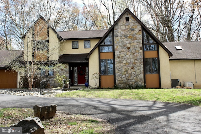 view of front of house featuring roof with shingles, stone siding, and stucco siding