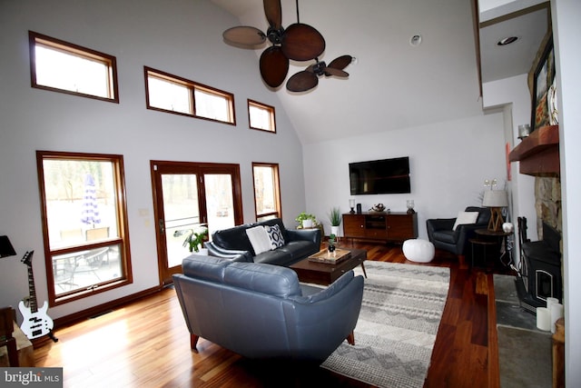 living area with a ceiling fan, high vaulted ceiling, plenty of natural light, and wood finished floors
