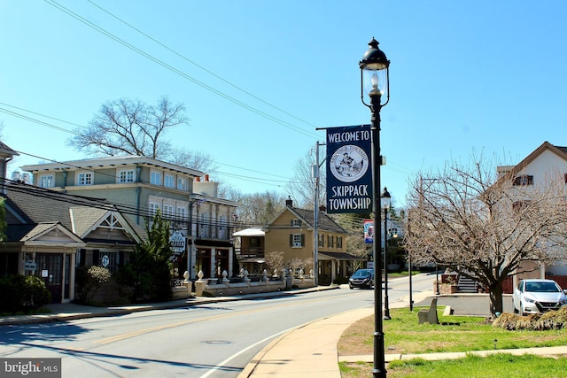 view of asphalt road featuring sidewalks, curbs, and street lights