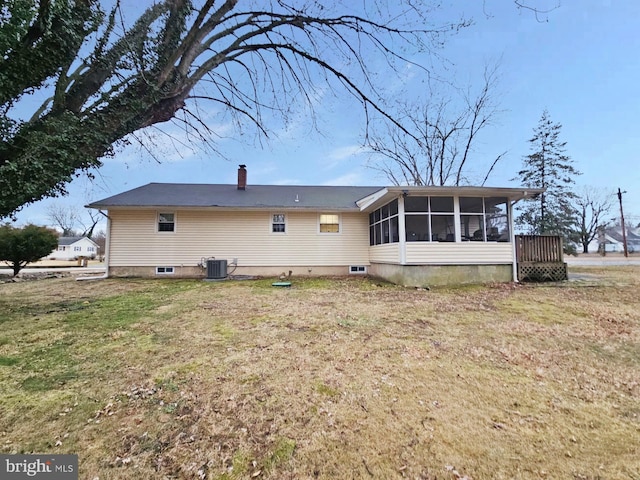 back of house with a sunroom, a chimney, central AC unit, and a lawn