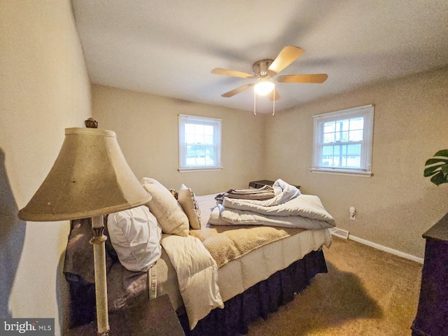 carpeted bedroom with visible vents, baseboards, and a ceiling fan