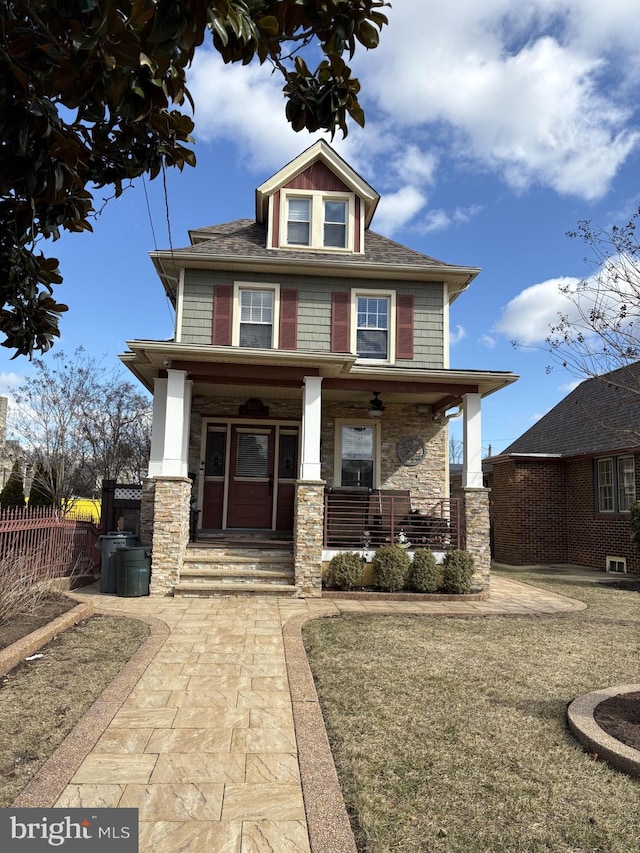 american foursquare style home with a porch, stone siding, and fence