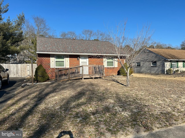 ranch-style home with fence, brick siding, and a shingled roof