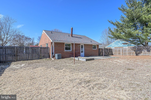 back of property with brick siding, central air condition unit, roof with shingles, a fenced backyard, and a patio area