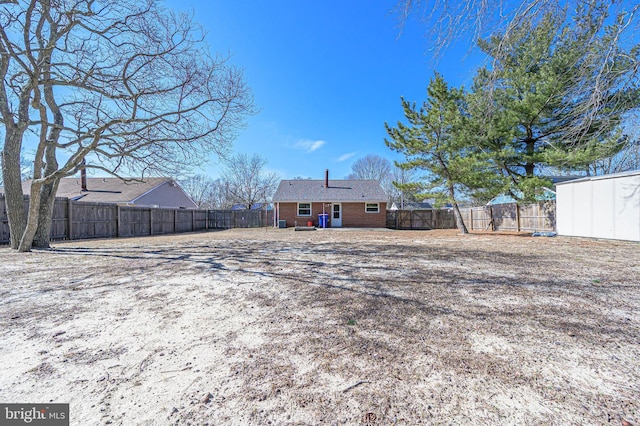 back of property featuring an outbuilding, a fenced backyard, brick siding, and a shed