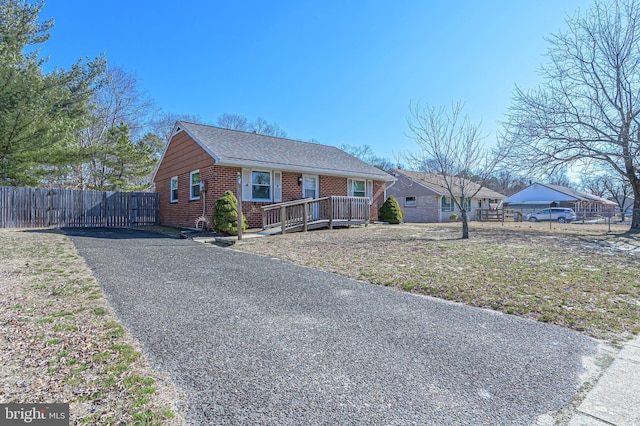 view of front of house featuring brick siding, driveway, and fence