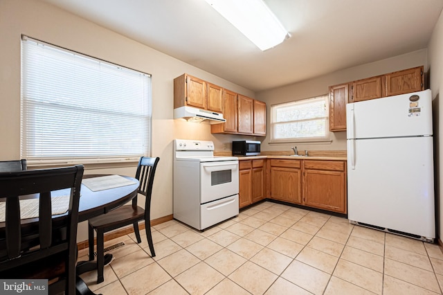 kitchen featuring under cabinet range hood, a sink, white appliances, light countertops, and light tile patterned floors