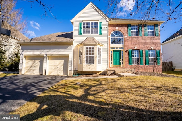 view of front of property with aphalt driveway, an attached garage, brick siding, and a front yard