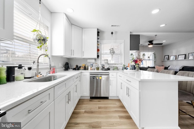 kitchen with visible vents, dishwasher, a breakfast bar area, a peninsula, and a sink