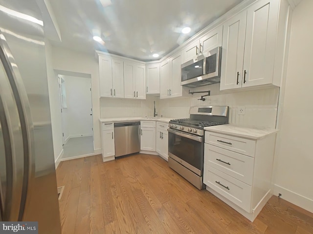 kitchen featuring light countertops, light wood-style flooring, appliances with stainless steel finishes, white cabinetry, and a sink