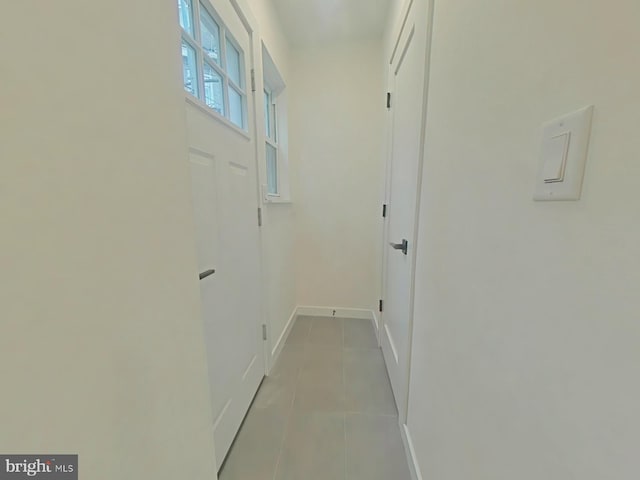 hall featuring light tile patterned floors and baseboards