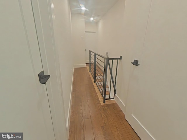 corridor featuring wood finished floors, an upstairs landing, and baseboards