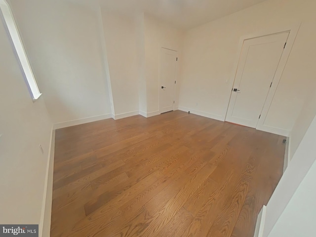 unfurnished room with baseboards and wood finished floors