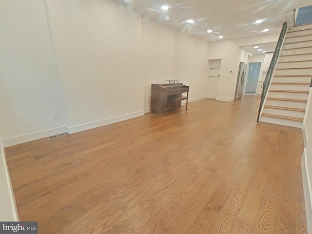 empty room featuring baseboards, stairway, and wood finished floors