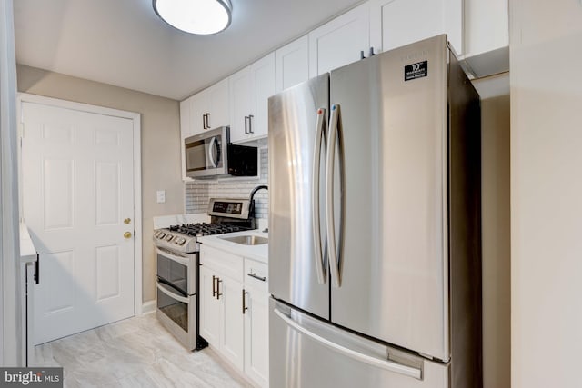 kitchen featuring appliances with stainless steel finishes, light countertops, white cabinets, and decorative backsplash