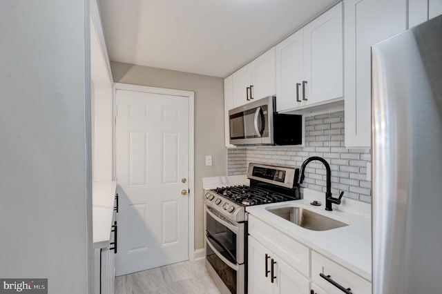 kitchen featuring backsplash, white cabinetry, stainless steel appliances, and a sink