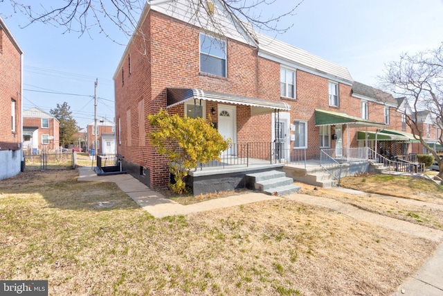 back of property with a yard, fence, and brick siding