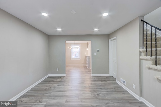 empty room featuring recessed lighting, visible vents, wood finished floors, baseboards, and stairs