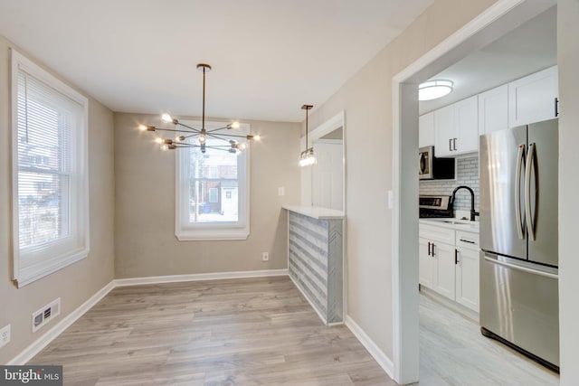 dining space with light wood-style flooring, visible vents, baseboards, and a notable chandelier