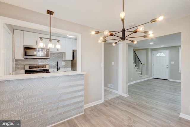 kitchen featuring a sink, visible vents, white cabinetry, light wood-style floors, and appliances with stainless steel finishes