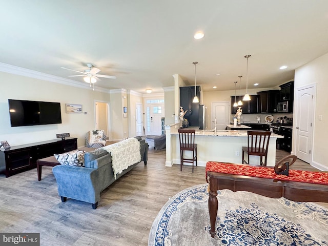 living room featuring recessed lighting, light wood-style flooring, and ornamental molding