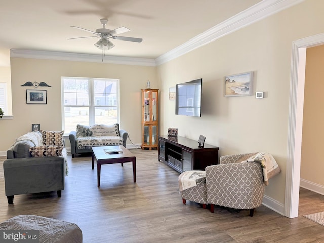 living area featuring ceiling fan, baseboards, wood finished floors, and crown molding