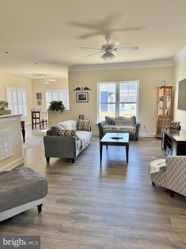 living area with visible vents, wood finished floors, baseboards, and ornamental molding