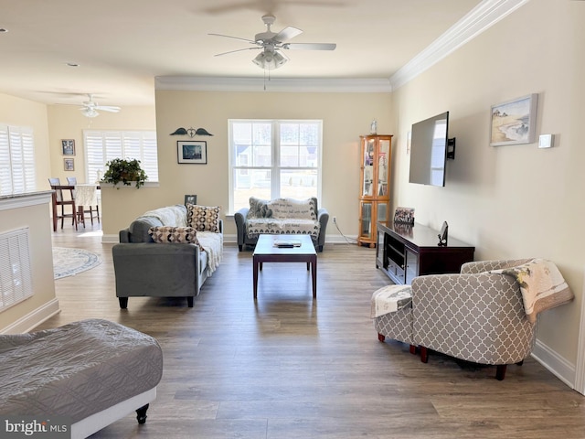 living room with a healthy amount of sunlight, wood finished floors, baseboards, and ornamental molding