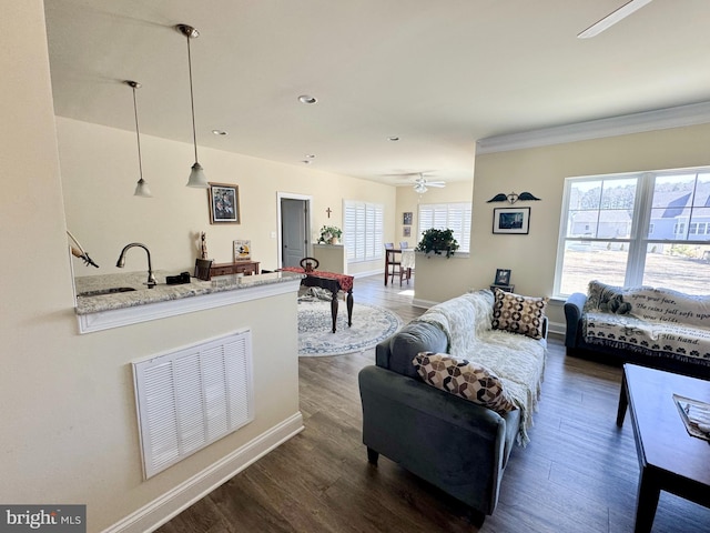 living room featuring visible vents, baseboards, and wood finished floors